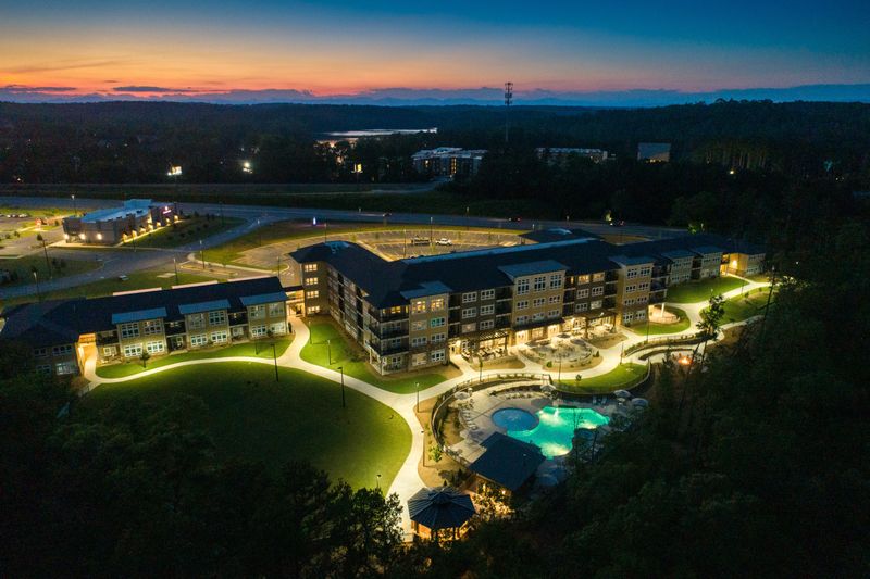 LED streetlamps cast a warm glow upon the pathway behind Lakeside Lodge Clemson as the last few orange and pink ribbons of sunlight drift wistfully below the horizon.