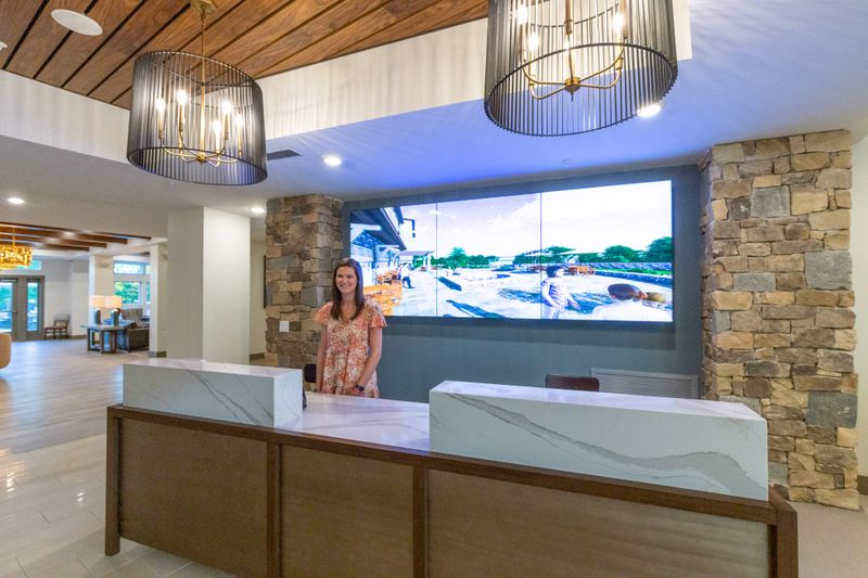 A smiling concierge awaits visitors at Lakeside Lodge's check-in desk.